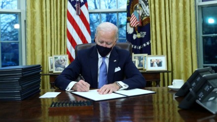 A photograph of US President Joe Biden signing Executive Orders in the Oval Office on his first day in office.