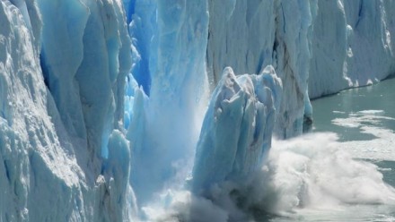 A photograph of a section of iceberg breaking off the main berg and plunging into the sea.