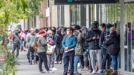 A large queue of people wearing hygiene masks outside Centrelink offices in Melbourne.