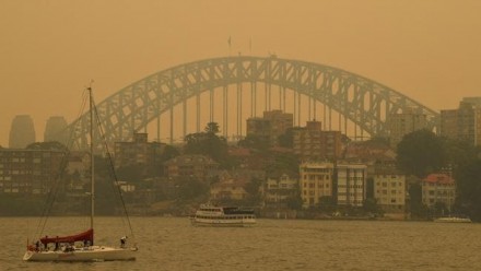 A photograph of Sydney Harbour Bridge, shrouded in orange bushfire smoke