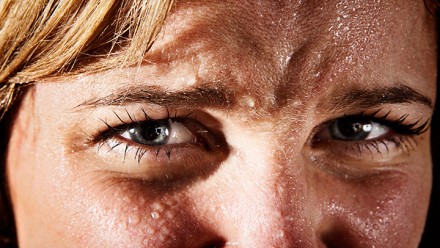 A woman&#039;s face, sweating profusely.