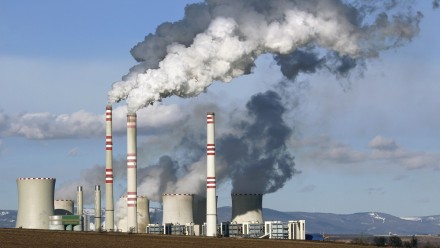A photograph of a coal fired power station, with smoke billowing out of the chimneys.