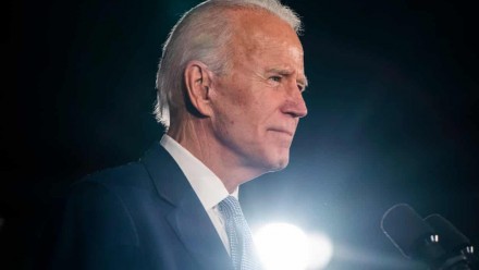A picture of Joe Biden dressed in a suit, looking to the right of the camera, with a dark background and a light shining up from the bottom of the image.