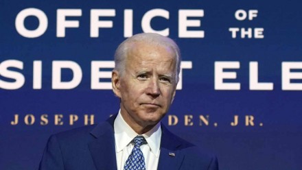 Joe Biden in a blue suit with a blue tie, looking towards the camera.
