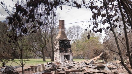 A fireplace remains standing in the rubble of a burnt property.