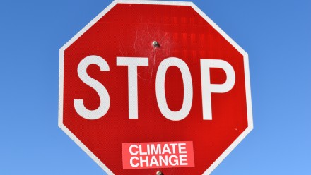 A stop sign has a sticker at the bottom saying &quot;climate change.&quot;