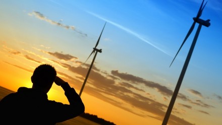 Silhouette of a man looking at wind turbines during sunset