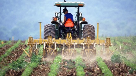 A farmer ploughing a field in a tractor.