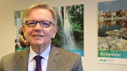 A photography of Prof Howard Bamsey, wearing a suit, smiling and looking towards the camera.