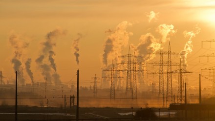 A photograph of a coal-fired power station under a hazy orange sky.