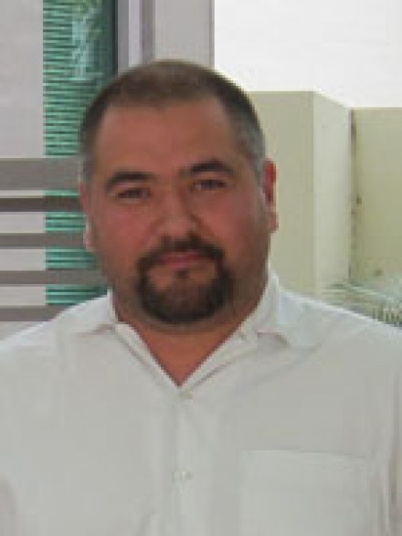 A photograph of Kirill Nourzhanov smiling and looking towards the camera.
