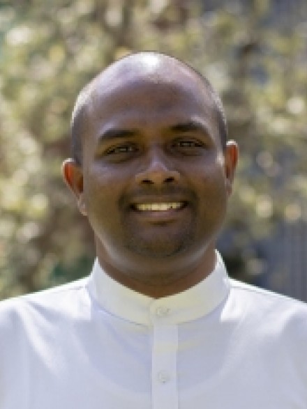 A photograph of Chalaka Fernando outdoors, smiling and looking towards the camera.