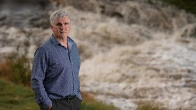 Professor Mark Howden standing in front of a raging river.