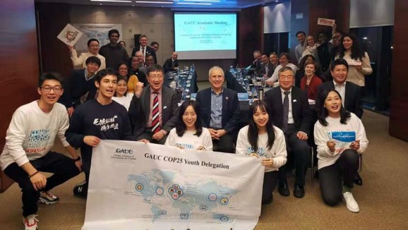 ANU staff and students at a GUAC meeting at COP25 holding a banner that says "GAUC COP25 Youthe Delegation"